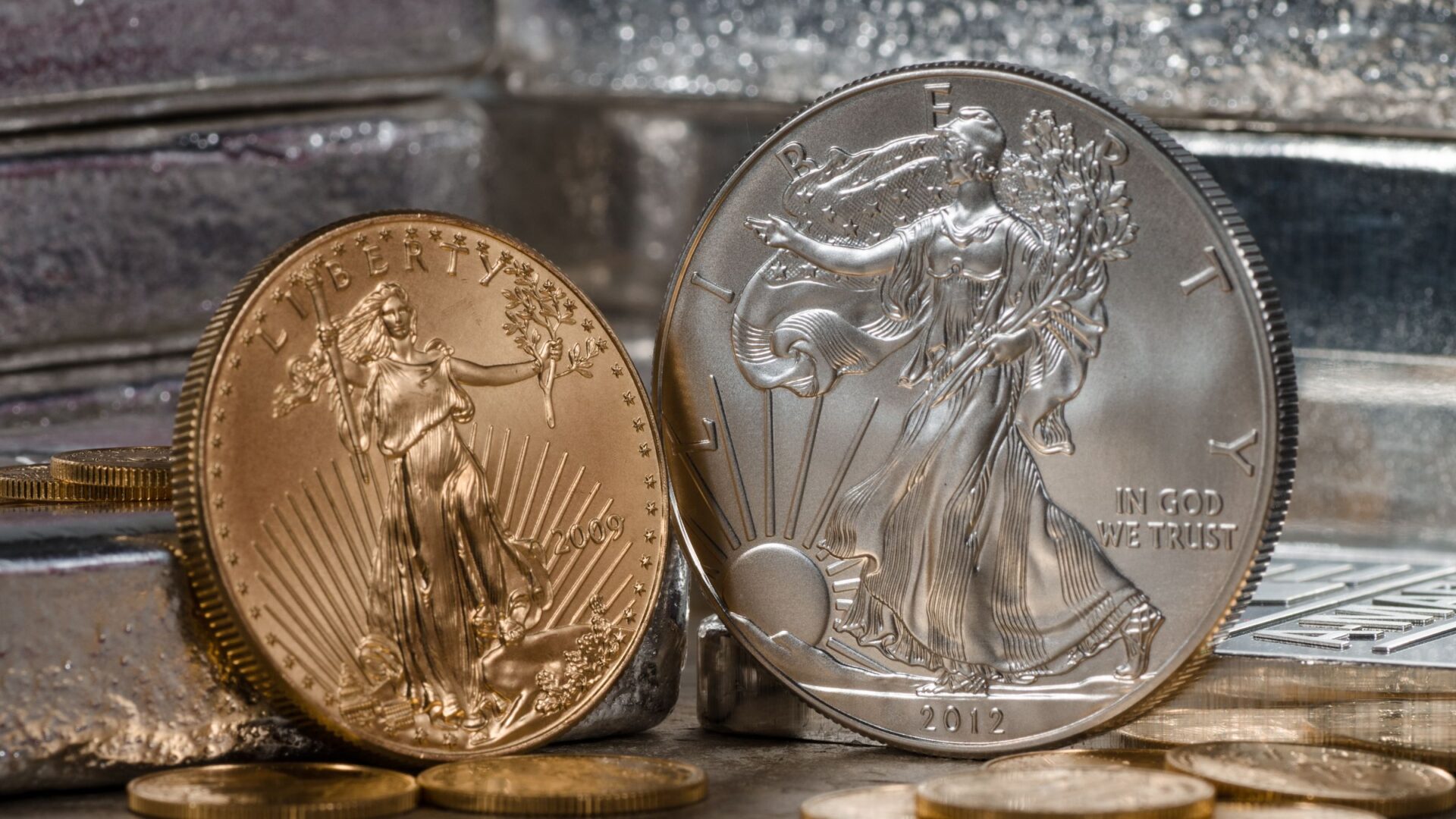 1 oz American Gold Eagle and American Silver Eagle coins in front of silver bullion bars