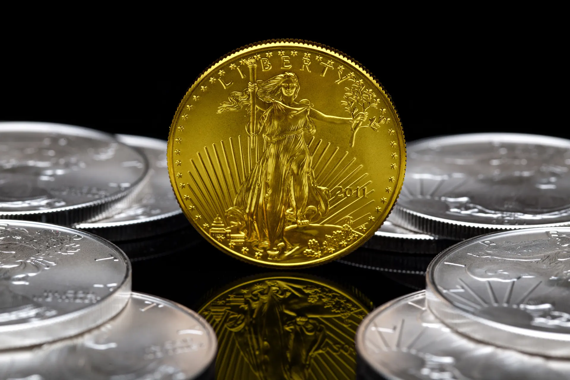 1 oz American Gold Eagle coin standing among American Silver Eagle coins