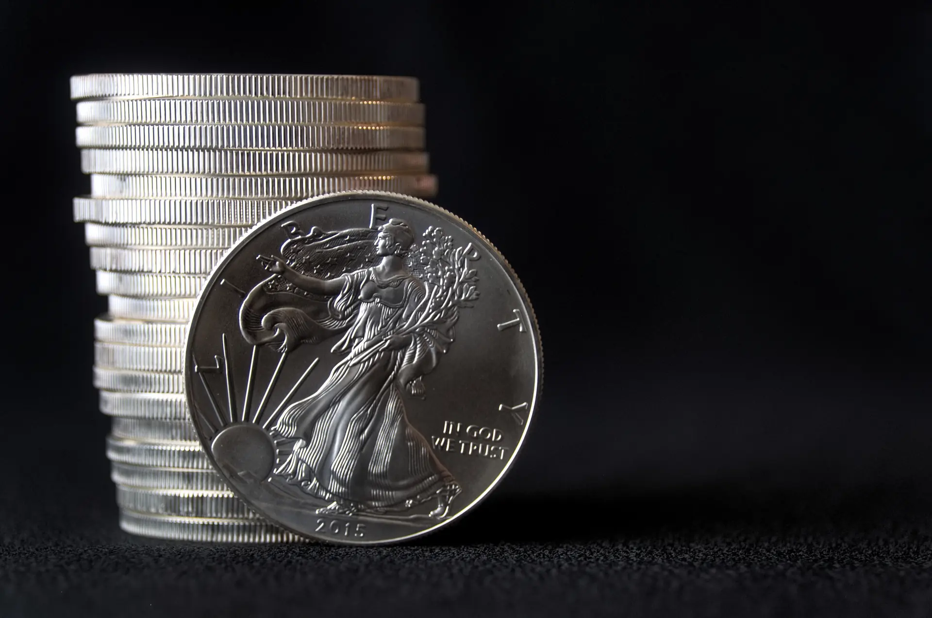 American Silver Eagle coin standing against a stack of Silver Eagles